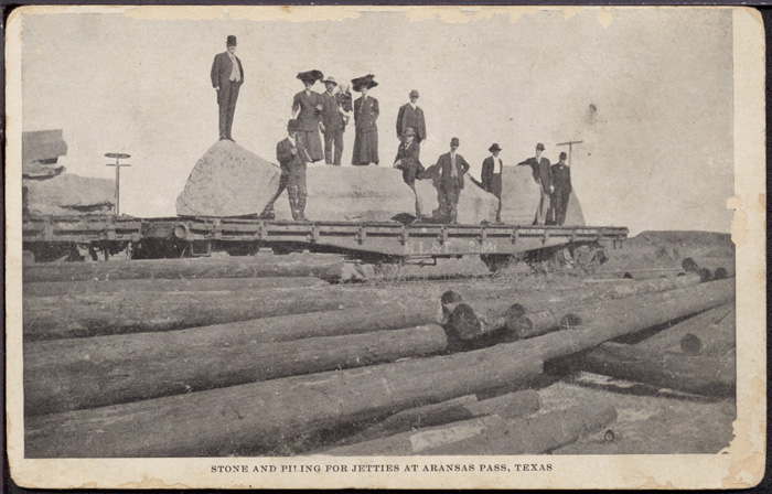 Sightseers viewing flat car of stones for use in jetty construction at Aransas Pass, ca. 1909. 